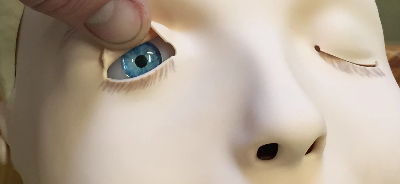 Blått öga på en docka öppnas försiktigt.