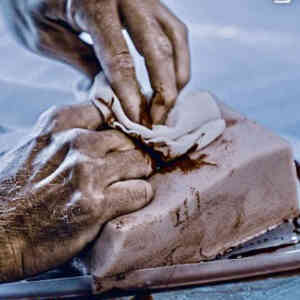 En person rengör en lerform med trasa