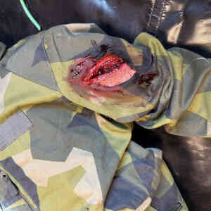 Skadad militäruniform med blodig reva.