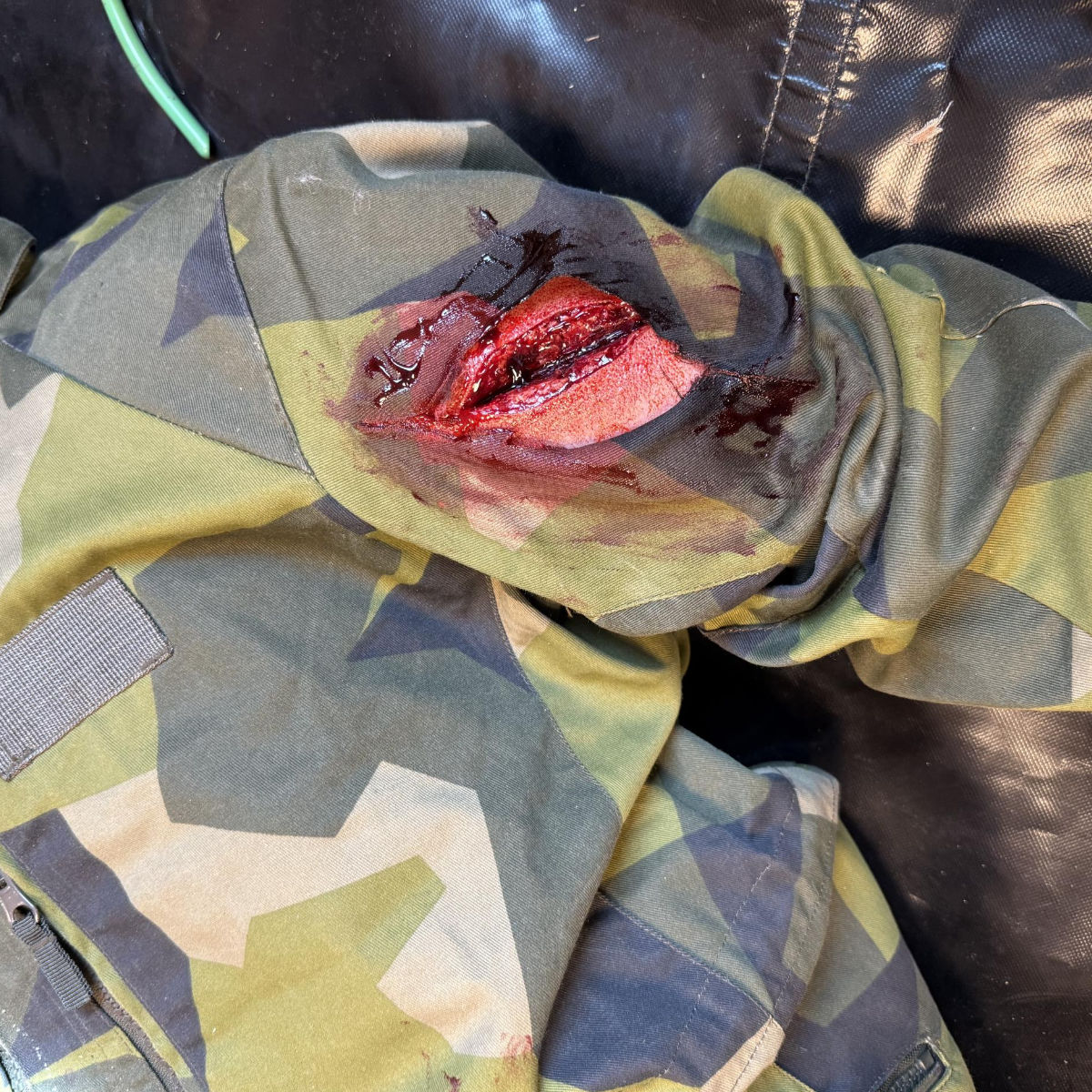 Skadad militäruniform med blodig reva.