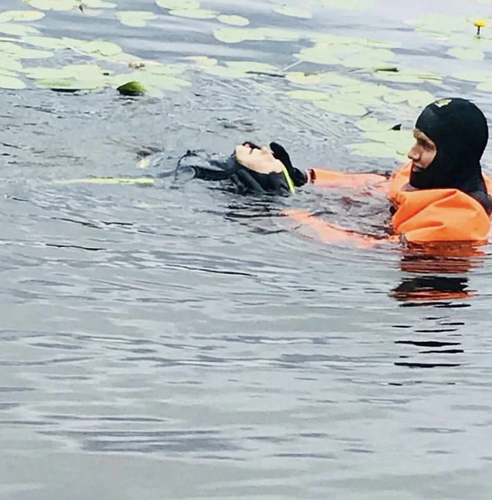 Person i orange dräkt räddar hund från vattnet.